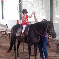 Niño jugando con aro en clase de equinoterpaia